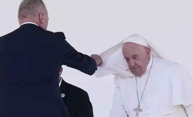 An aide assists Pope Francis with his cape after he gave an address during meeting with young people in the Sir John Guise Stadium in Port Moresby, Papua New Guinea, Monday, Sept. 9, 2024. (AP Photo/Mark Baker)