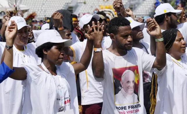 People hold hands as Pope Francis gives an address during meeting with young people in the Sir John Guise Stadium in Port Moresby, Papua New Guinea, Monday, Sept. 9, 2024. (AP Photo/Mark Baker)