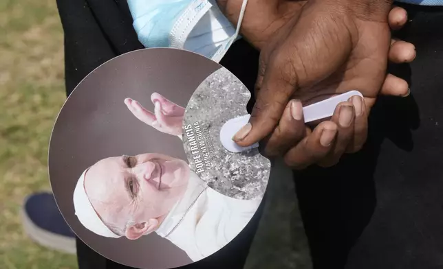 An attendee hold a fan with the Pope's likeness as Pope Francis gives an address during meeting with young people in the Sir John Guise Stadium in Port Moresby, Papua New Guinea, Monday, Sept. 9, 2024. (AP Photo/Mark Baker)