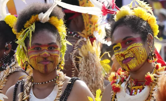 Women wear face paint and traditional headdress before Pope Francis gives an address during meeting with young people in the Sir John Guise Stadium in Port Moresby, Papua New Guinea, Monday, Sept. 9, 2024. (AP Photo/Mark Baker)