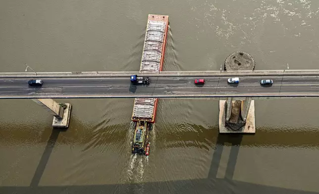 A tugboat pushes a barge under the Remanso bridge on the Paraguay River in Mariano R. Alonso, Paraguay, Monday, Sept. 9, 2024. Water levels have plunged to their lowest-ever level amid a drought, according to Paraguay's Meteorology and Hydrology Office. (AP Photo/Jorge Saenz)