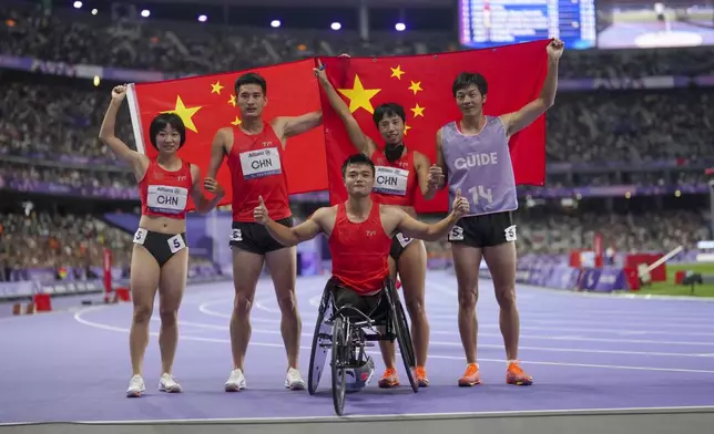 China team poses after winning the gold and setting a new world record in the 4x100 m. universal relay at the 2024 Paralympics, Friday, Sept. 6, 2024, in Paris, France. From left, Wen Xiaoyan, Wang Hao, Hu Yang and Zhou Guohua, with her guide. (AP Photo/Thibault Camus)