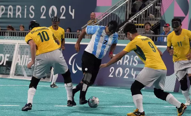 Argentina's Maximiliano Espinillo fights for the ball against Brazil's Ricardinho, left, and Brazil's Tiago da Silva, second right, during the semifinal blind football match between Argentina and Brazil at the 2024 Paralympics, Thursday, Sept. 5, 2024, in Paris, France. (AP Photo/Michel Euler)