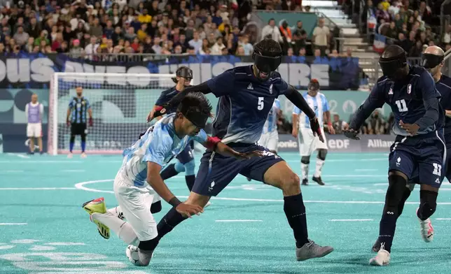 Argentina's Osvaldo Fernandez, left, falls as he fights for the ball with France's Hakim Arezki during the blind football gold medal match at the 2024 Paralympics, Saturday, Sept. 7, 2024, in Paris, France. (AP Photo/Christophe Ena)