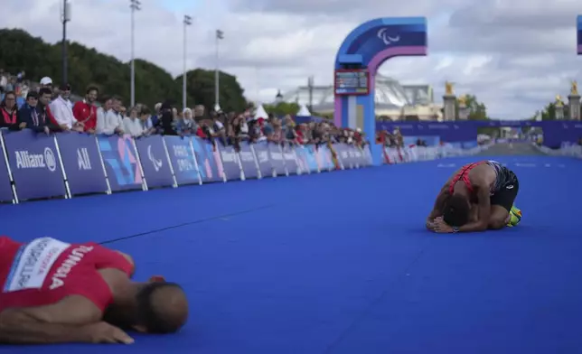 Japan's Tadashi Horikoshi, right, and Tunisia's Hatem Nasrallah lie on the ground after the men's marathon T12 at the 2024 Paralympics, Sunday, Sept. 8, 2024, in Paris, France. (AP Photo/Thibault Camus)