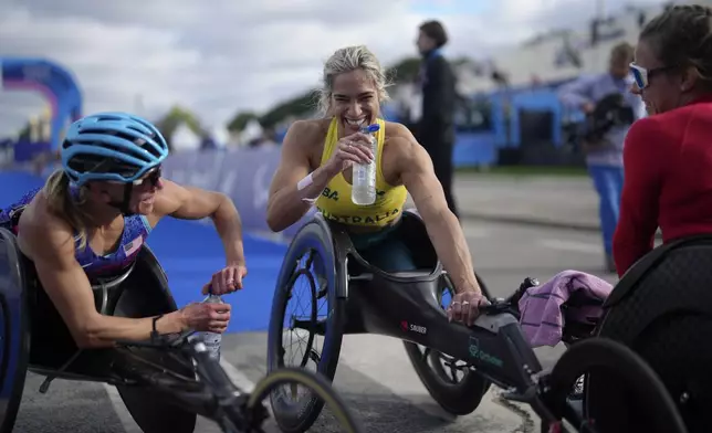 Silver medalist Australia's Madison de Rozario, centre, bronze medalist Susannah Scaroni of the U.S., left, and winner Switzerland's Catherine Debrunner speak after the women's marathon T54 at the 2024 Paralympics, Sunday, Sept. 8, 2024, in Paris, France. (AP Photo/Thibault Camus)