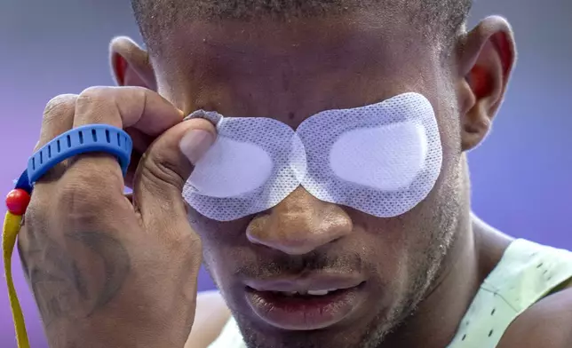 Chris Kinda, of Namibia, removes the mask that prevents him from seeing as he competes at Men's 100m -T11 at the Stade de France stadium, during the 2024 Paralympics, Wednesday, Sept. 4, 2024, in Paris, France. (AP Photo/Emilio Morenatti)