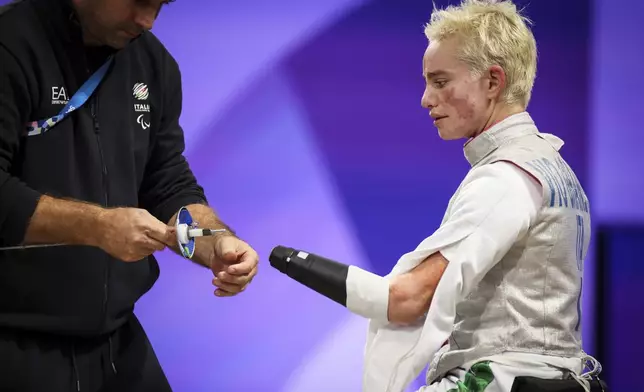 Italy's Beatrice Maria Vio Grandis coach installs her prosthesis before to compete against China's Su Kang during the women's foil wheelchair fencing Category B Repechage Round 4 at the 2024 Paralympics, Wednesday, Sept. 4, 2024, in Paris, France. (AP Photo/Thomas Padilla)