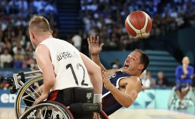 Jake Williams of the U.S. eyes the ball as he falls during the wheelchair basketball men's gold medal match at the 2024 Paralympics, Saturday, Sept. 7, 2024, in Paris, France. (AP Photo/Thomas Padilla)