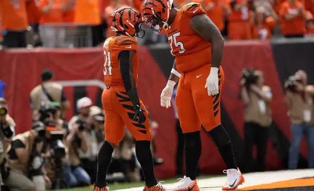 Cincinnati Bengals running back Zack Moss (31) celebrates with teammate Orlando Brown Jr. (75) after scoring on a 5-yard touchdown run during the second half of an NFL football game against the New England Patriots, Sunday, Sept. 8, 2024, in Cincinnati. (AP Photo/Carolyn Kaster)