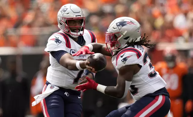 New England Patriots quarterback Jacoby Brissett (7) hands the ball off to running back Rhamondre Stevenson (38) during the first half of an NFL football game against the Cincinnati Bengals, Sunday, Sept. 8, 2024, in Cincinnati. (AP Photo/Carolyn Kaster)