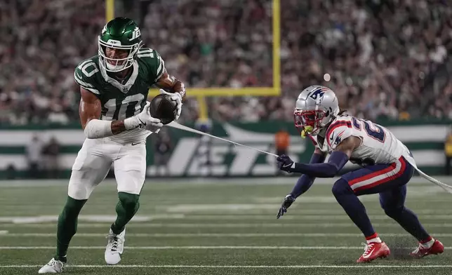 New York Jets wide receiver Allen Lazard (10) runs for a touchdown despite the efforts of New England Patriots cornerback Alex Austin (28) during the first quarter of an NFL football game, Thursday, Sept. 19, 2024, in East Rutherford, N.J. (AP Photo/Julia Demaree Nikhinson)