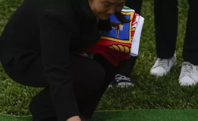 Keiko Fujimori places a flower on the grave of her father, former President Alberto Fujimori, during his funeral n Lima, Peru, Saturday, Sept. 14, 2024. (AP Photo/Guadalupe Pardo)