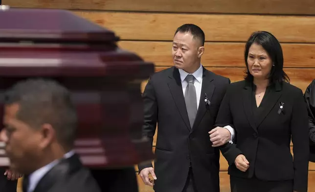 Keiko Fujimori, right, and her brother Kenji stand by as pallbearers carry the coffin of their father, former President Alberto Fujimori, out of Keiko's home the day after he died in Lima, Peru, Thursday, Sept. 12, 2024. (AP Photo/Guadalupe Pardo)