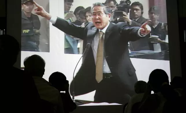 FILE - Peru's former President Alberto Fujimori is seen gesturing on a screen during the first day of his trial on charges of alleged human rights violations and corruption during his government at a police base in Lima, Dec. 10, 2007. (AP Photo/Martin Mejia, File)