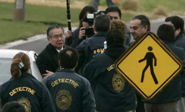 FILE - Chilean police officers surround former Peru's President Alberto Fujimori, left, as he leaves his house in Santiago to be extradited to Peru to face human rights and corruption charges, early Sept. 22, 2007. His daughter Keiko Fujimori announced in a post on X that he died of cancer on Wednesday, September 11, 2024. (AP Photo/Claudio Santana, File)