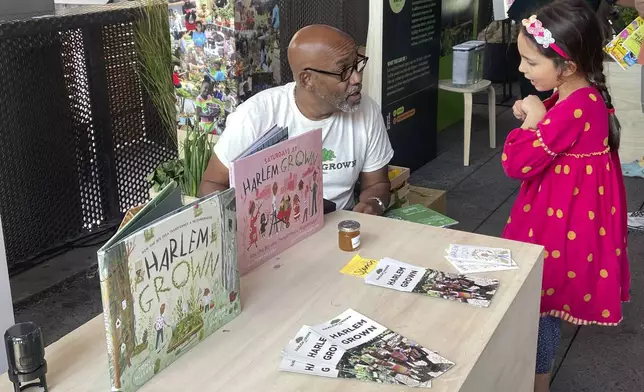 Tony Hillery, founder and CEO of Harlem Grown, a nonprofit that runs urban farms and works with children, speaks with a young fan at the Climate Science Fair on Sunday, Sept. 22, 2024 in New York. (AP Photo/Thalia Beaty)