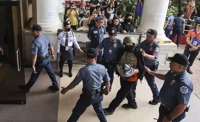 Apollo Carreon Quiboloy, wearing a helmet and flak jacket, a Filipino preacher charged with human trafficking, enters the Pasig Regional Trial Court in Pasig City, Philippines, Friday, Sept. 13, 2024. (AP Photo/Gerard Carreon)