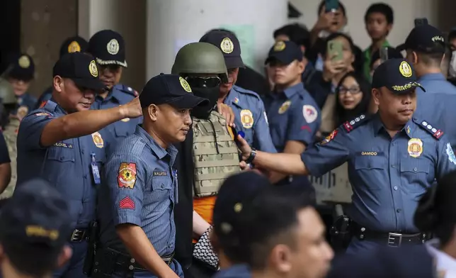 Apollo Carreon Quiboloy, center, wearing a helmet and flak jacket, a Filipino preacher charged with human trafficking, leaves the Pasig Regional Trial Court in Pasig City, Philippines, Friday, Sept. 13, 2024. (AP Photo/Gerard Carreon)