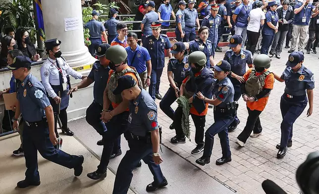 People, in green helmet, charged with human trafficking, enter the Pasig Regional Trial Court, walking after Apollo Carreon Quiboloy, a Filipino preacher, in Pasig City, Philippines, Friday, Sept. 13, 2024. (AP Photo/Gerard Carreon)