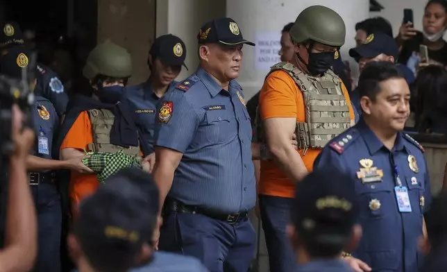 People, in green helmet, charged with human trafficking, leave the Pasig Regional Trial Court, walking after Apollo Carreon Quiboloy, a Filipino preacher, in Pasig City, Philippines, Friday, Sept. 13, 2024. (AP Photo/Gerard Carreon)