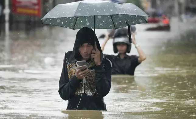 A resident wades along a flooded street caused by heavy rains from Tropical Storm Yagi, locally called Enteng, on Monday, Sept. 2, 2024, in Cainta, Rizal province, Philippines. (AP Photo/Aaron Favila)