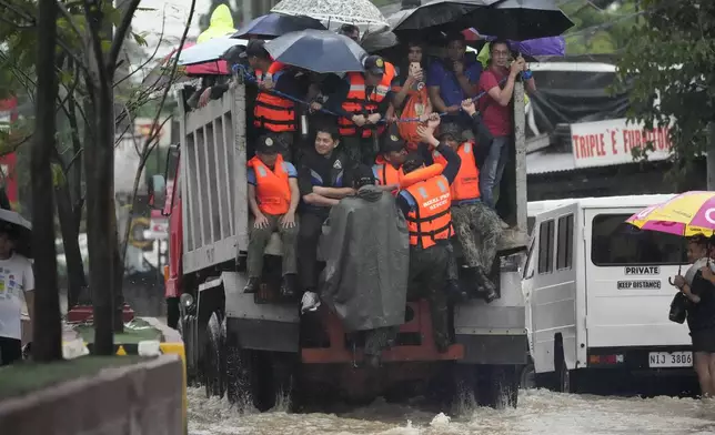 Rescuers and residents ride a truck as they cross a flooded street caused by heavy rains from Tropical Storm Yagi, locally called Enteng, in Cainta, Rizal province, Philippines, Monday, Sept. 2, 2024. (AP Photo/Aaron Favila)