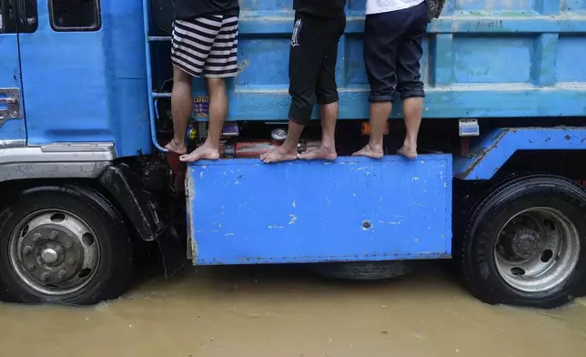 Residents ride a truck as they negotiate a flooded street caused by heavy rains from Tropical Storm Yagi, locally called Enteng, in Cainta, Rizal province, Philippines, Monday, Sept. 2, 2024. (AP Photo/Aaron Favila)