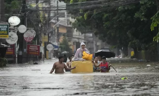 A resident rides an old refrigerator to avoid a flooded street caused by heavy rains from Tropical Storm Yagi, locally called Enteng, on Monday, Sept. 2, 2024, in Cainta, Rizal province, Philippines. (AP Photo/Aaron Favila)