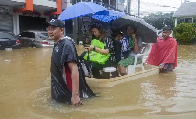 Residents ride on an improvised float through flood waters caused by heavy rains from Tropical Storm Yagi, locally called Enteng, as they return to their homes on Monday, Sept. 2, 2024, in Cainta, Rizal province, Philippines. (AP Photo/Aaron Favila)