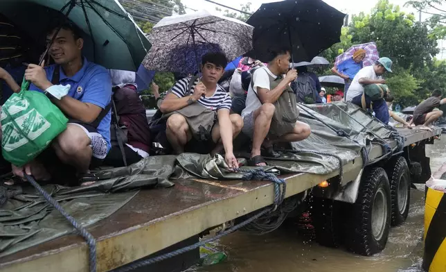 Residents ride a truck as they negotiate a flooded street caused by heavy rains from Tropical Storm Yagi, locally called Enteng, in Cainta, Rizal province, Philippines, Monday, Sept. 2, 2024. (AP Photo/Aaron Favila)