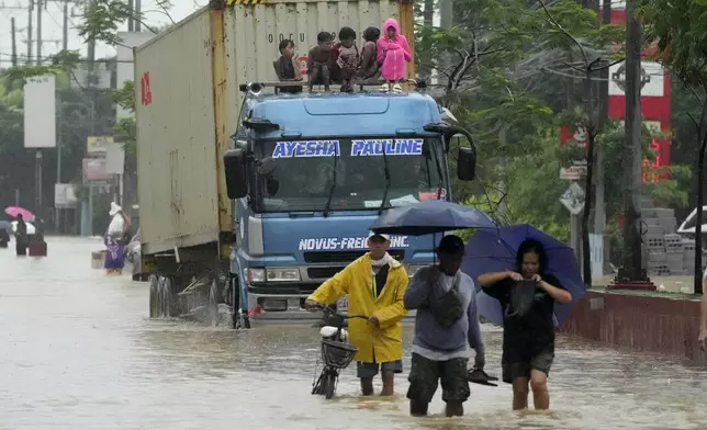 Children ride on top of a truck to avoid floodwaters caused by heavy rains from Tropical Storm Yagi, locally called Enteng, on Monday, Sept. 2, 2024, in Cainta, Rizal province, Philippines. (AP Photo/Aaron Favila)