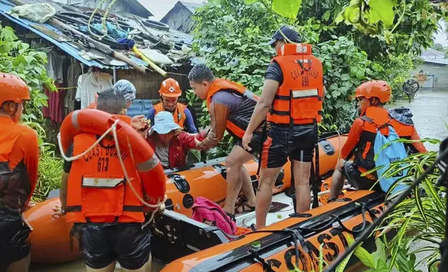 In this photo provided by the Philippine Coast Guard, rescuers use a rubber boat as they evacuate residents to higher grounds following floods due to a tropical storm in Allen, Northern Samar province, Philippines Sunday, Sept. 1, 2024. (Philippine Coast Guard via AP)