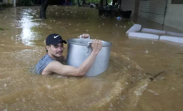 A resident uses a large pot to keep him afloat as he negotiates a flooded street caused by heavy rains from Tropical Storm Yagi, locally called Enteng, in Cainta, Rizal province, Philippines, Monday, Sept. 2, 2024. (AP Photo/Aaron Favila)