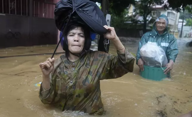 Residents carry their belongings as they wade along a flooded street caused by heavy rains from Tropical Storm Yagi, locally called Enteng, on Monday, Sept. 2, 2024, in Cainta, Rizal province, Philippines. (AP Photo/Aaron Favila)