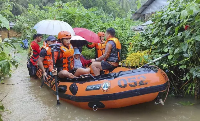 In this photo provided by the Philippine Coast Guard, rescuers use a rubber boat as they evacuate residents to higher grounds following floods due to a tropical storm in Allen, Northern Samar province, Philippines Sunday, Sept. 1, 2024. (Philippine Coast Guard via AP)