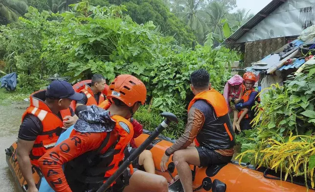 In this photo provided by the Philippine Coast Guard, rescuers use a rubber boat as they evacuate residents to higher grounds following floods due to a tropical storm in Allen, Northern Samar province, Philippines Sunday, Sept. 1, 2024. (Philippine Coast Guard via AP)