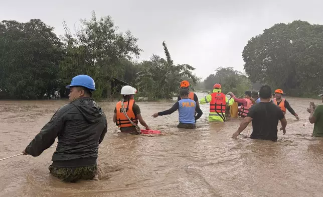 Rescuers help residents as they negotiate floods caused by powerful Typhoon Krathon locally called "Typhoon Julian" at Bacarra, Ilocos Norte province, northern Philippines on Monday, Sept. 30, 2024. (AP Photo/Bernie Dela Cruz)