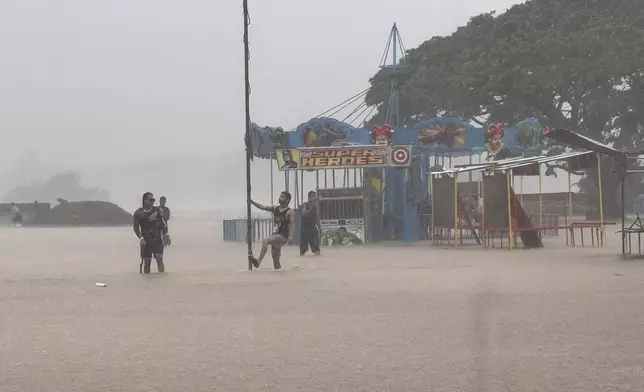 Residents negotiate floods caused by powerful Typhoon Krathon locally called "Typhoon Julian" at Bacarra, Ilocos Norte province, northern Philippines on Monday, Sept. 30, 2024. (AP Photo/Bernie Dela Cruz)