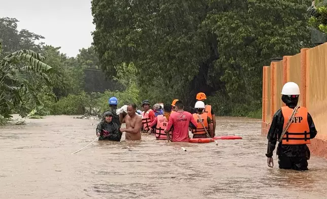 Rescuers help residents as they negotiate floods caused by powerful Typhoon Krathon locally called "Typhoon Julian" at Bacarra, Ilocos Norte province, northern Philippines on Monday, Sept. 30, 2024. (AP Photo/Bernie Dela Cruz)