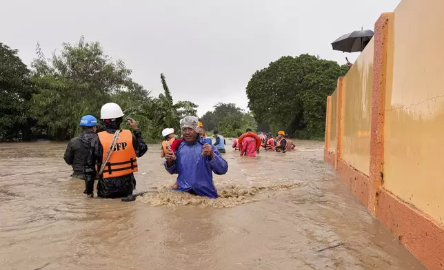 Residents negotiate floods caused by powerful Typhoon Krathon locally called "Typhoon Julian" at Bacarra, Ilocos Norte province, northern Philippines on Monday, Sept. 30, 2024. (AP Photo/Bernie Dela Cruz)