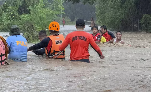 Rescuers help residents evacuate to higher grounds as they negotiate floods caused by powerful Typhoon Krathon locally called "Typhoon Julian" at Bacarra, Ilocos Norte province, northern Philippines on Monday, Sept. 30, 2024. (AP Photo/Bernie Dela Cruz)