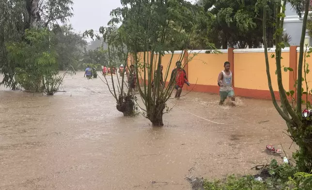 Residents negotiate floods caused by powerful Typhoon Krathon locally called "Typhoon Julian" at Bacarra, Ilocos Norte province, northern Philippines on Monday, Sept. 30, 2024. (AP Photo/Bernie Dela Cruz)