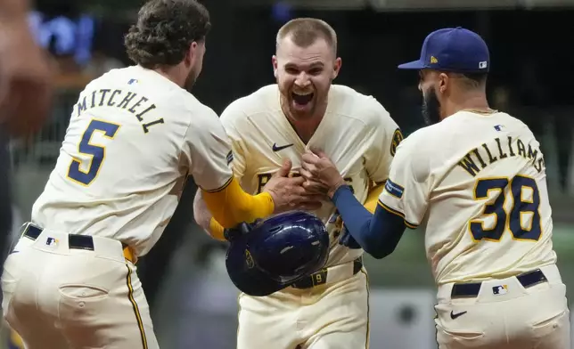 Milwaukee Brewers' Jake Bauers is congratulated by Devin Williams and Garrett Mitchell after hitting a walk-off RBI single after a baseball game against the Philadelphia Phillies Wednesday, Sept. 18, 2024, in Milwaukee. (AP Photo/Morry Gash)