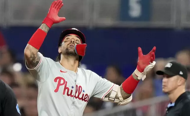 Philadelphia Phillies' Nick Castellanos, left, reacts after hitting a single during the fourth inning of a baseball game against the Miami Marlins, Friday, Sept. 6, 2024, in Miami. (AP Photo/Lynne Sladky)