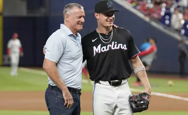 Former Miami Marlins player Jeff Connie, left, stands with his son, right, Marlins right fielder Griffin Conine, after throwing a ceremonial first pitch before a baseball game against the Philadelphia Phillies, Friday, Sept. 6, 2024, in Miami. (AP Photo/Lynne Sladky)