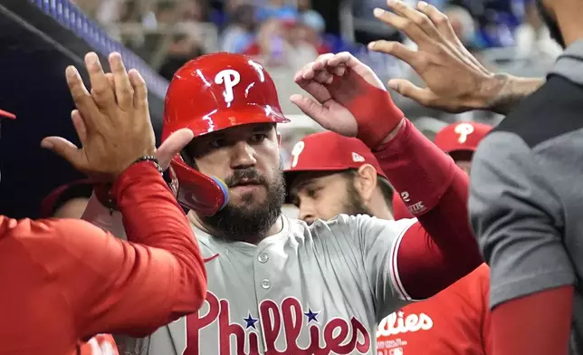 Philadelphia Phillies' Kyle Schwarber is congratulated in the dugout after scoring on a single hit by Bryce Harper during the first inning of a baseball game against the Miami Marlins, Friday, Sept. 6, 2024, in Miami. (AP Photo/Lynne Sladky)