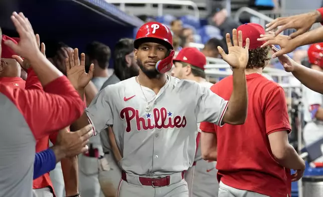 Philadelphia Phillies' Johan Rojas is congratulated in the dugout after scoring on a single hit by Bryce Harper during the ninth inning of a baseball game against the Miami Marlins, Sunday, Sept. 8, 2024, in Miami. (AP Photo/Lynne Sladky)