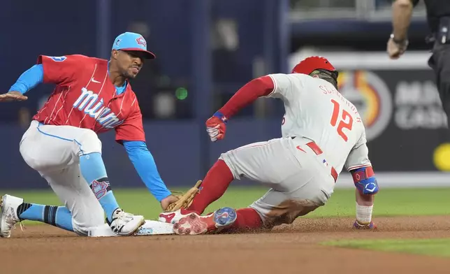 Philadelphia Phillies' Kyle Schwarber (12) slides into second base as Miami Marlins second baseman Otto Lopez (61) is late with the tag during the first inning of a baseball game, Saturday, Sept. 7, 2024, in Miami. (AP Photo/Marta Lavandier)