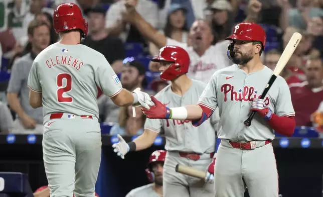 Philadelphia Phillies' Kody Clemens (2) is met by Kyle Schwarber, right, after scoring on a double hit by Johan Rojas during the fifth inning of a baseball game against the Miami Marlins, Friday, Sept. 6, 2024, in Miami. (AP Photo/Lynne Sladky)